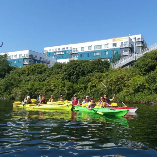 People kayaking and smiling at camera.