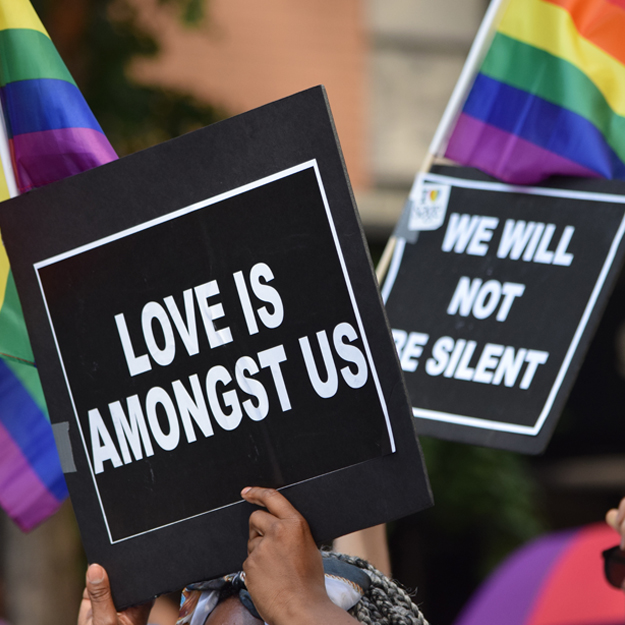 Woman holding up sign that says "Love is Amongst Us"