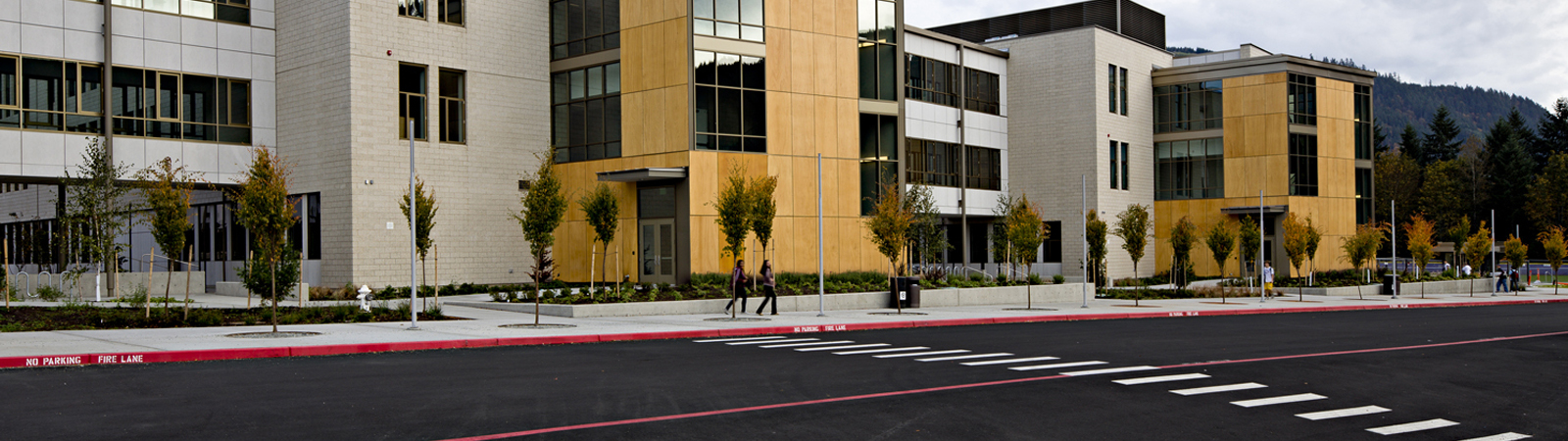 Outside of School with Two People Walking on Sidewalk